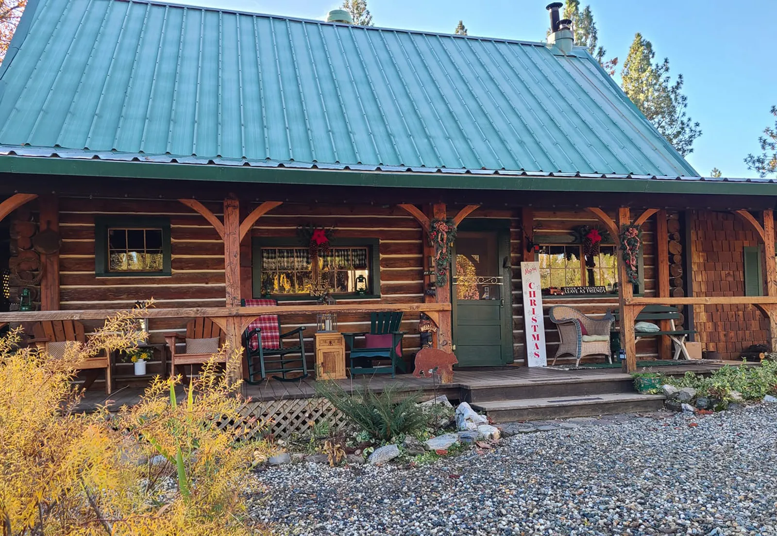 The log lodge at The Davies Family Inn, with its green metal roof and a covered porch of rocking chairs, on an autumn morning